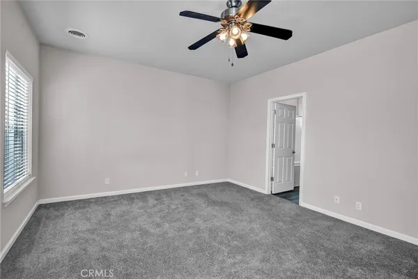 an empty room with windows and fan