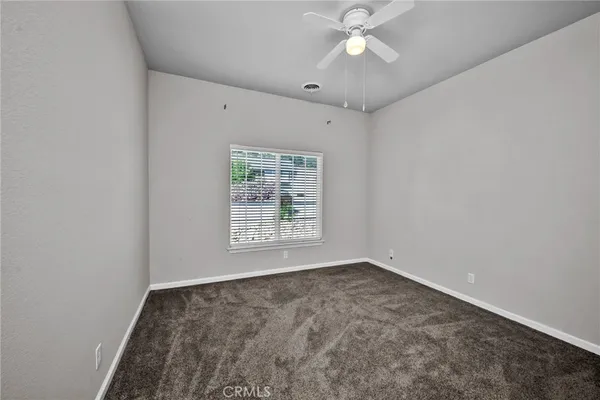 an empty room with a chandelier fan and windows