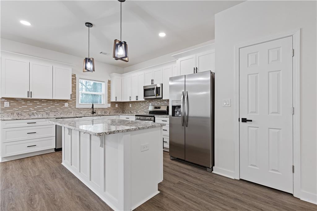 3272 Corktree Trail Lithonia, GA 30038 - Photo 6 of 22 a kitchen with stainless steel appliances granite countertop a refrigerator a sink dishwasher a stove and white cabinets with wooden floor