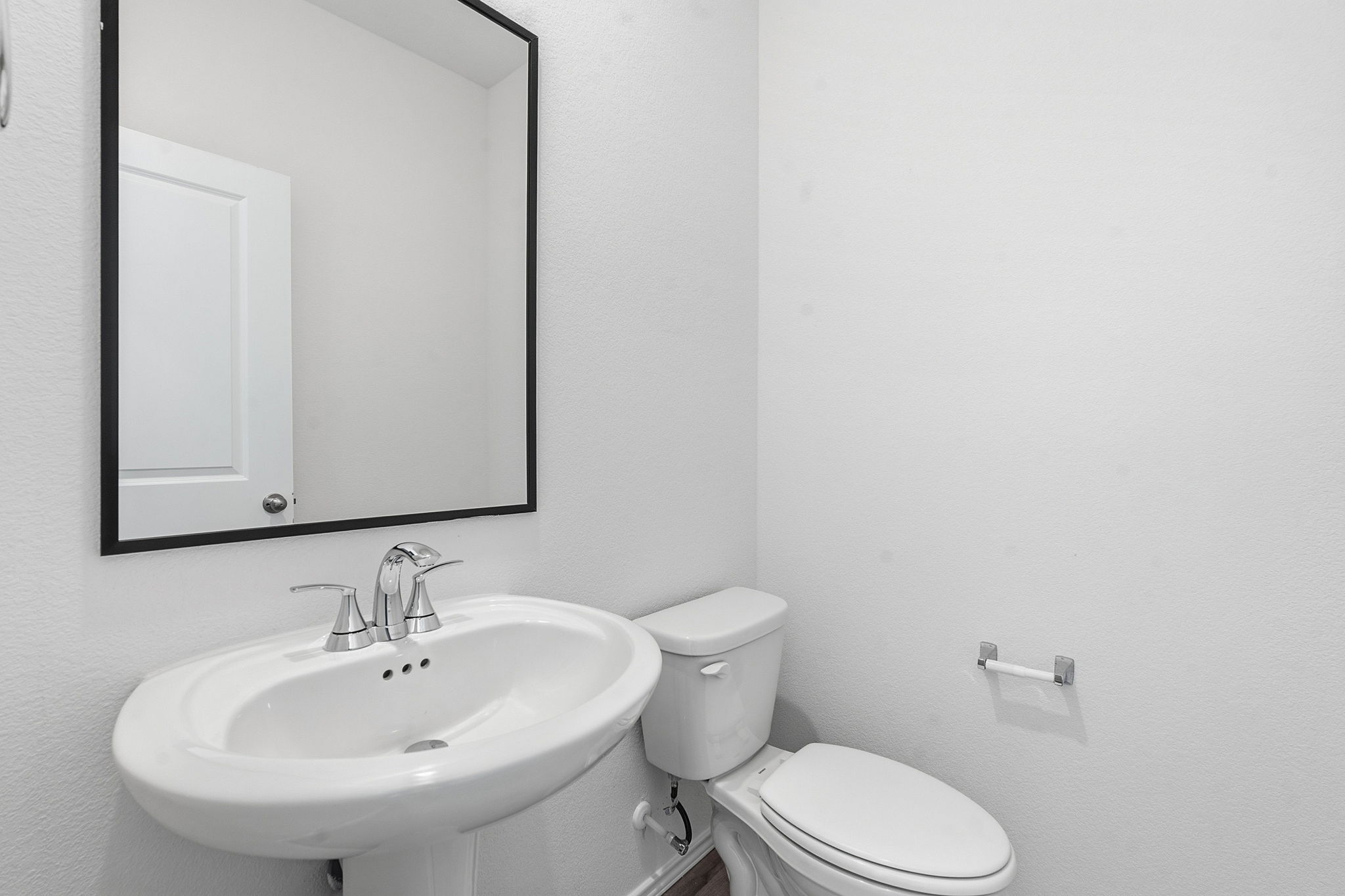 164 Cinnabar Lane, Unit 5 Kyle, TX 78640 - Photo 19 of 21 Pedestal sink with chrome faucet set, complemented by a rectangular mirror with a black frame