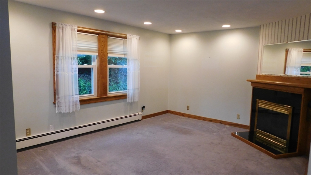 414 Cedar Street Dedham, MA 02026 - Photo 10 of 24 a view of an empty room with a fireplace and a window