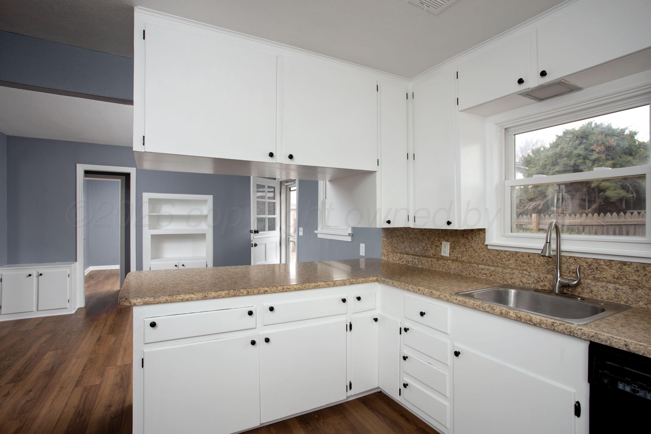 4815 Southwest 10th Avenue Amarillo, TX 79106 - Photo 7 of 21 a kitchen with granite countertop a sink window and cabinets