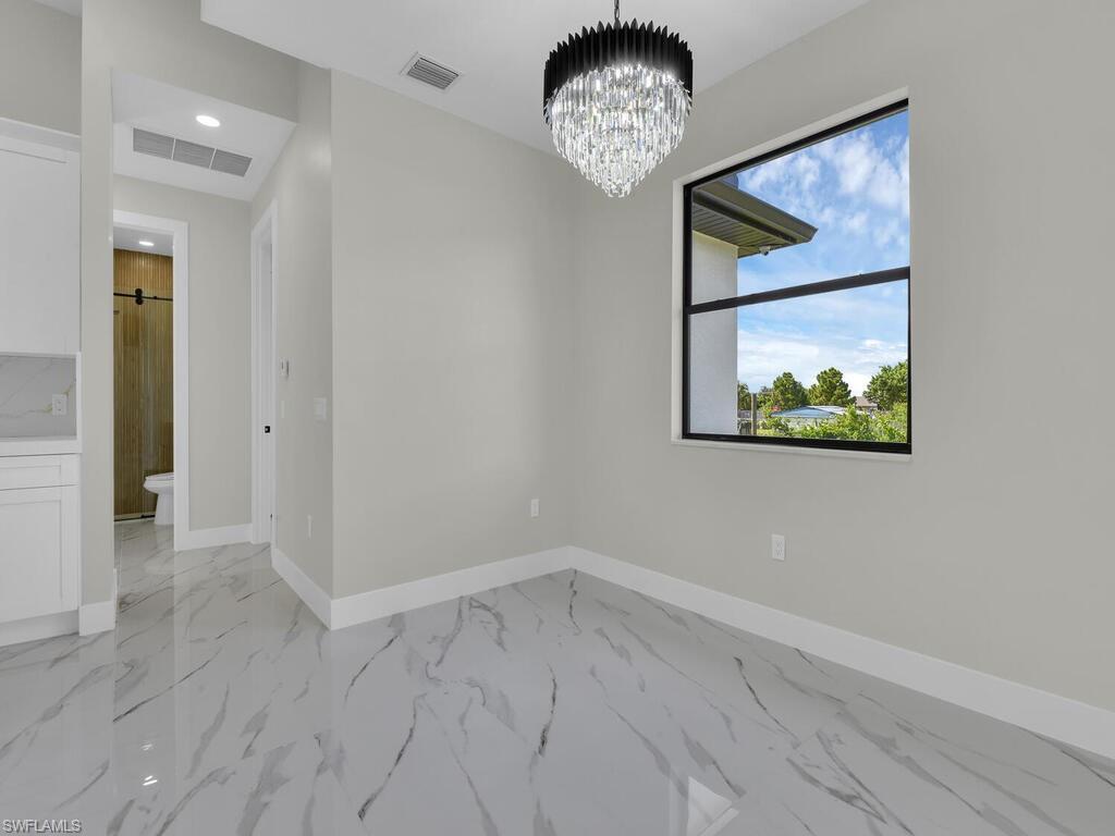 3300 3rd Street Southwest Lehigh Acres, FL 33976 - Photo 11 of 21 Spare room featuring a chandelier, light marble finish floors, and recessed lighting