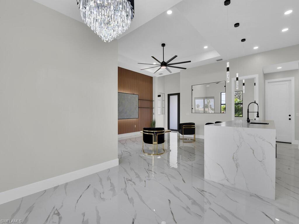 3300 3rd Street Southwest Lehigh Acres, FL 33976 - Photo 12 of 21 Kitchen with hanging light fixtures, a kitchen island with sink, light marble finish flooring, a chandelier, and a ceiling fan