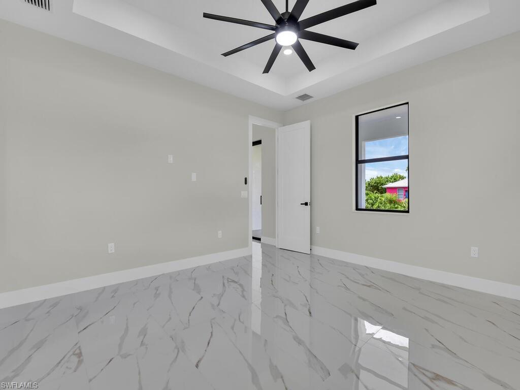 3300 3rd Street Southwest Lehigh Acres, FL 33976 - Photo 14 of 21 Spare room featuring a raised ceiling, light marble finish flooring, and ceiling fan