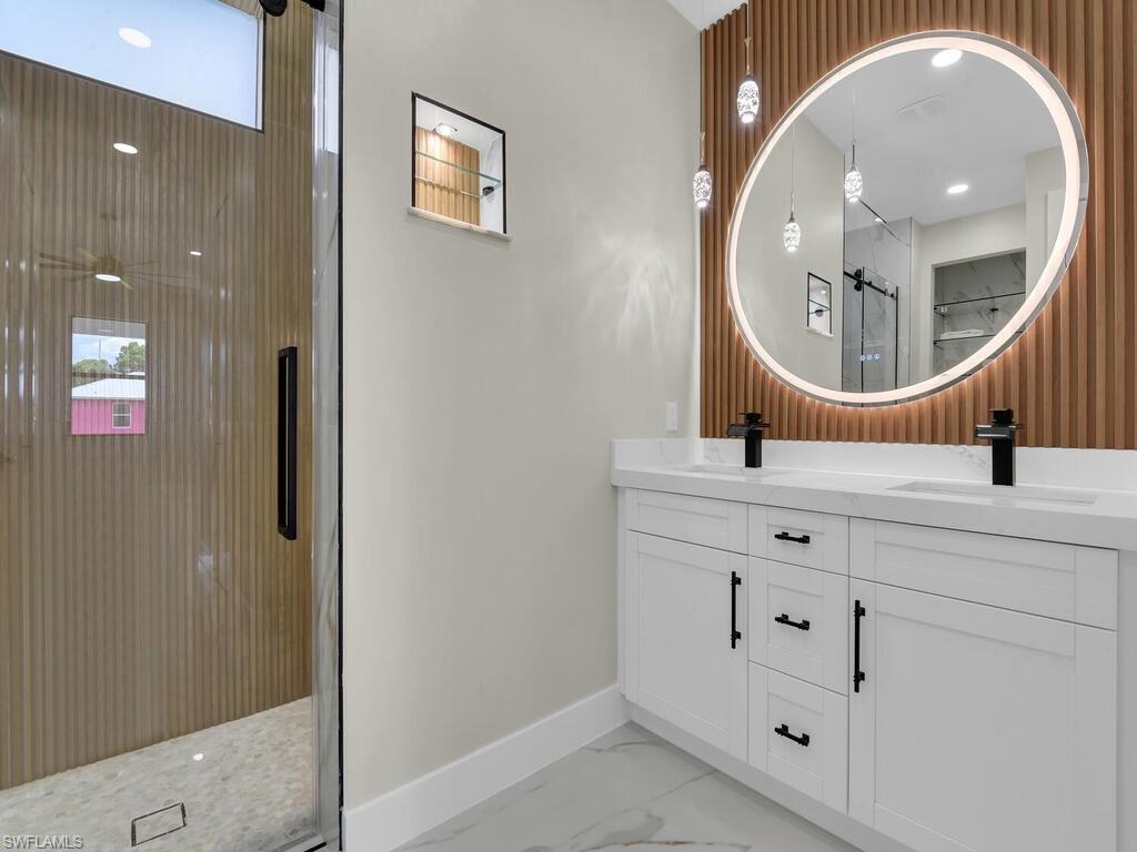 3300 3rd Street Southwest Lehigh Acres, FL 33976 - Photo 17 of 21 Bathroom with light marble finish floors, double vanity, a shower with shower door, and plenty of natural light
