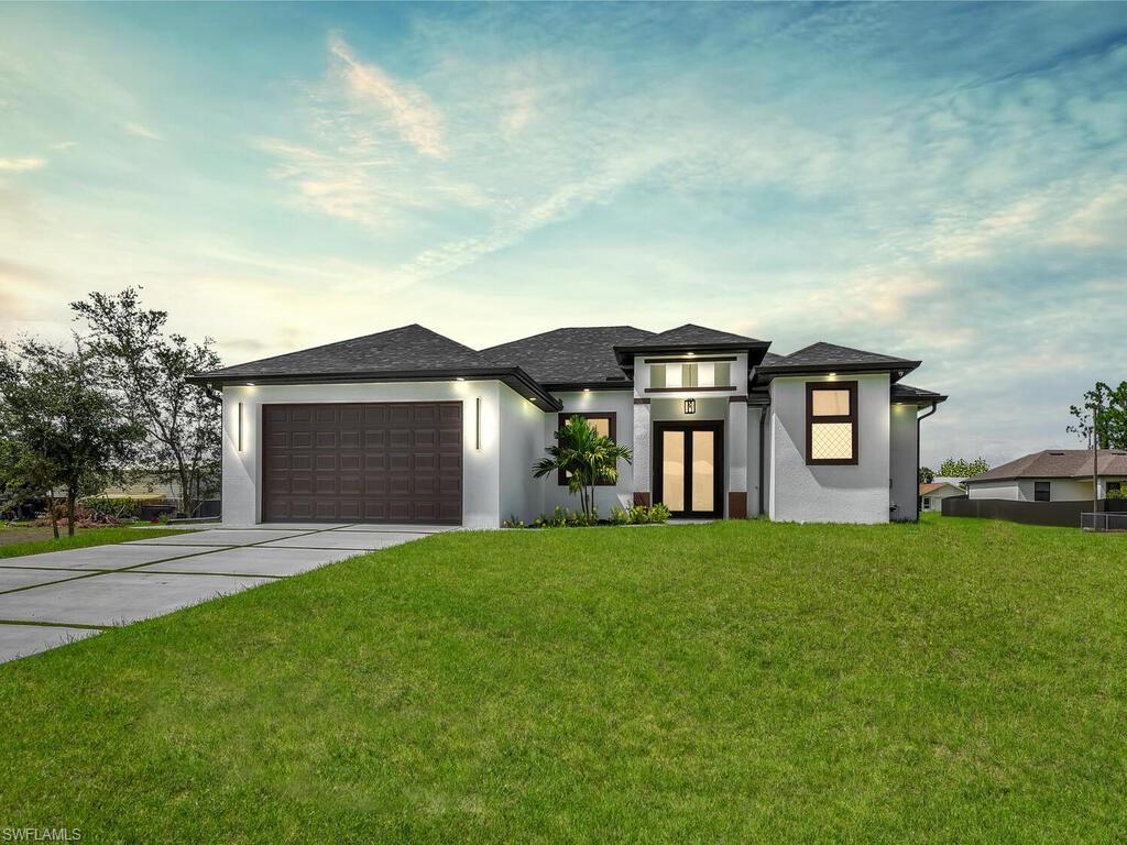 3300 3rd Street Southwest Lehigh Acres, FL 33976 - Photo 2 of 21 Prairie-style home featuring stucco siding, a garage, a front lawn, driveway, and a shingled roof