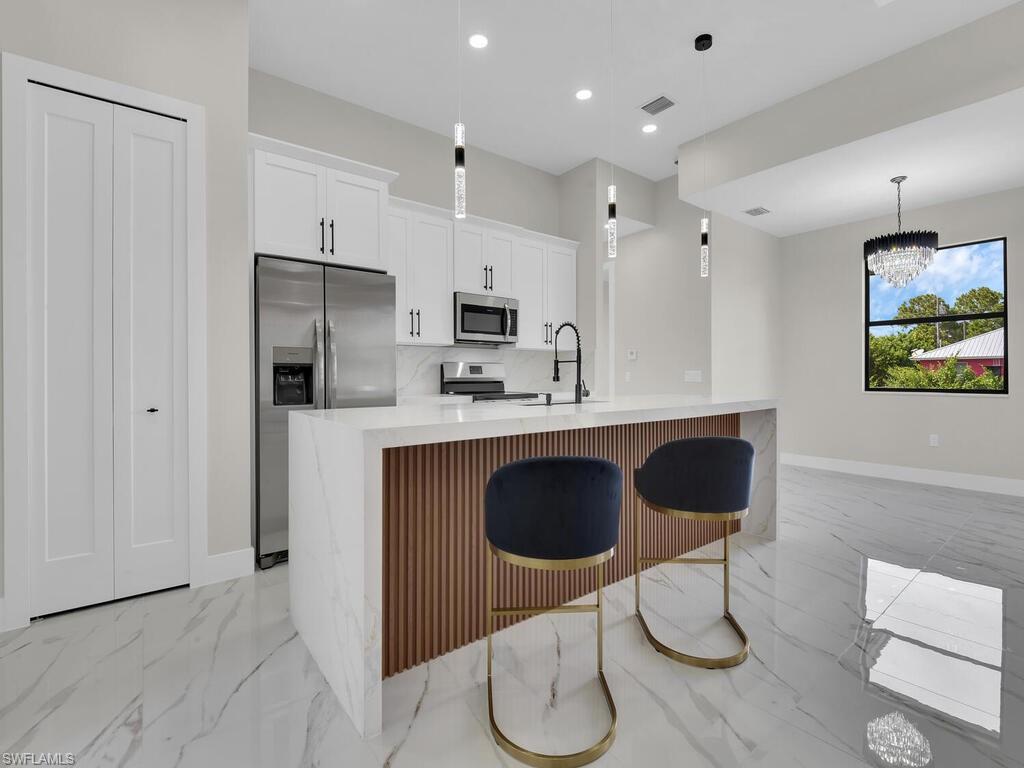 3300 3rd Street Southwest Lehigh Acres, FL 33976 - Photo 6 of 21 Kitchen with light stone counters, stainless steel appliances, light marble finish floors, pendant lighting, and recessed lighting