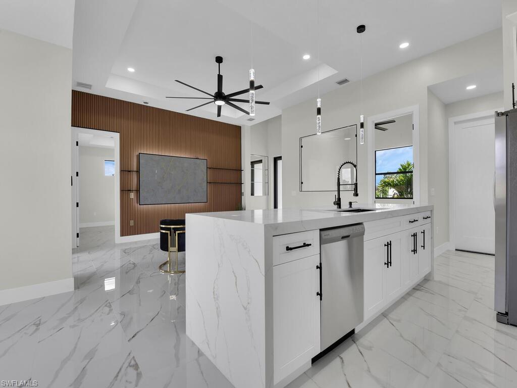 3300 3rd Street Southwest Lehigh Acres, FL 33976 - Photo 9 of 21 Kitchen featuring white cabinets, a raised ceiling, hanging light fixtures, a ceiling fan, and wooden walls