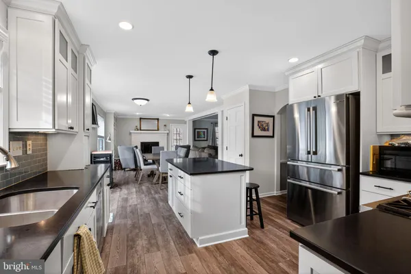 a kitchen with stainless steel appliances granite countertop a refrigerator a stove top oven a sink dishwasher and white cabinets with wooden floor