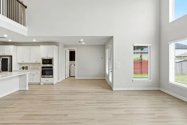 a view of a big room with wooden floor and kitchen view