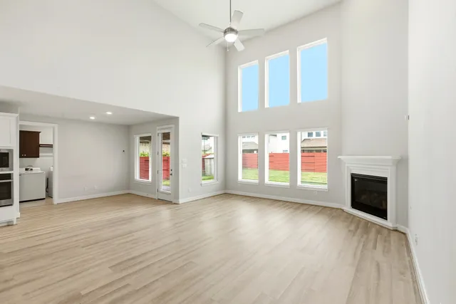 a view of an empty room with kitchen and window
