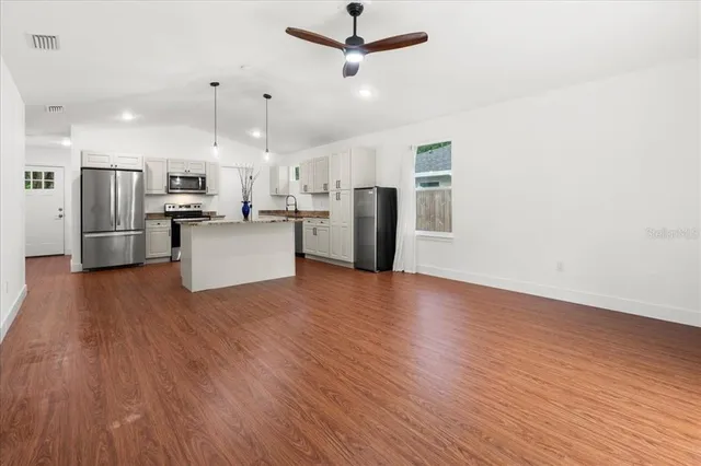 an open kitchen with wooden floor and stainless steel appliances