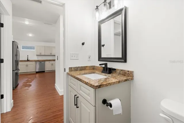 a en suite bathroom with a granite countertop sink and a mirror