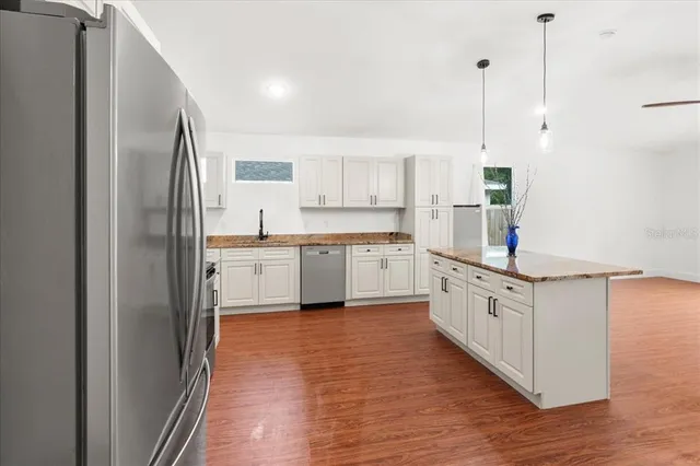 a kitchen with stainless steel appliances granite countertop a sink a stove and a refrigerator