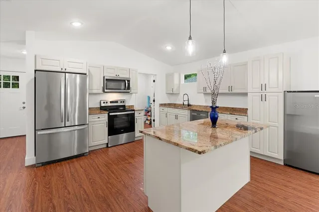 a kitchen with stainless steel appliances granite countertop a refrigerator a stove a sink and a microwave