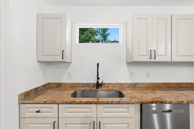 a kitchen with granite countertop white cabinets and a sink