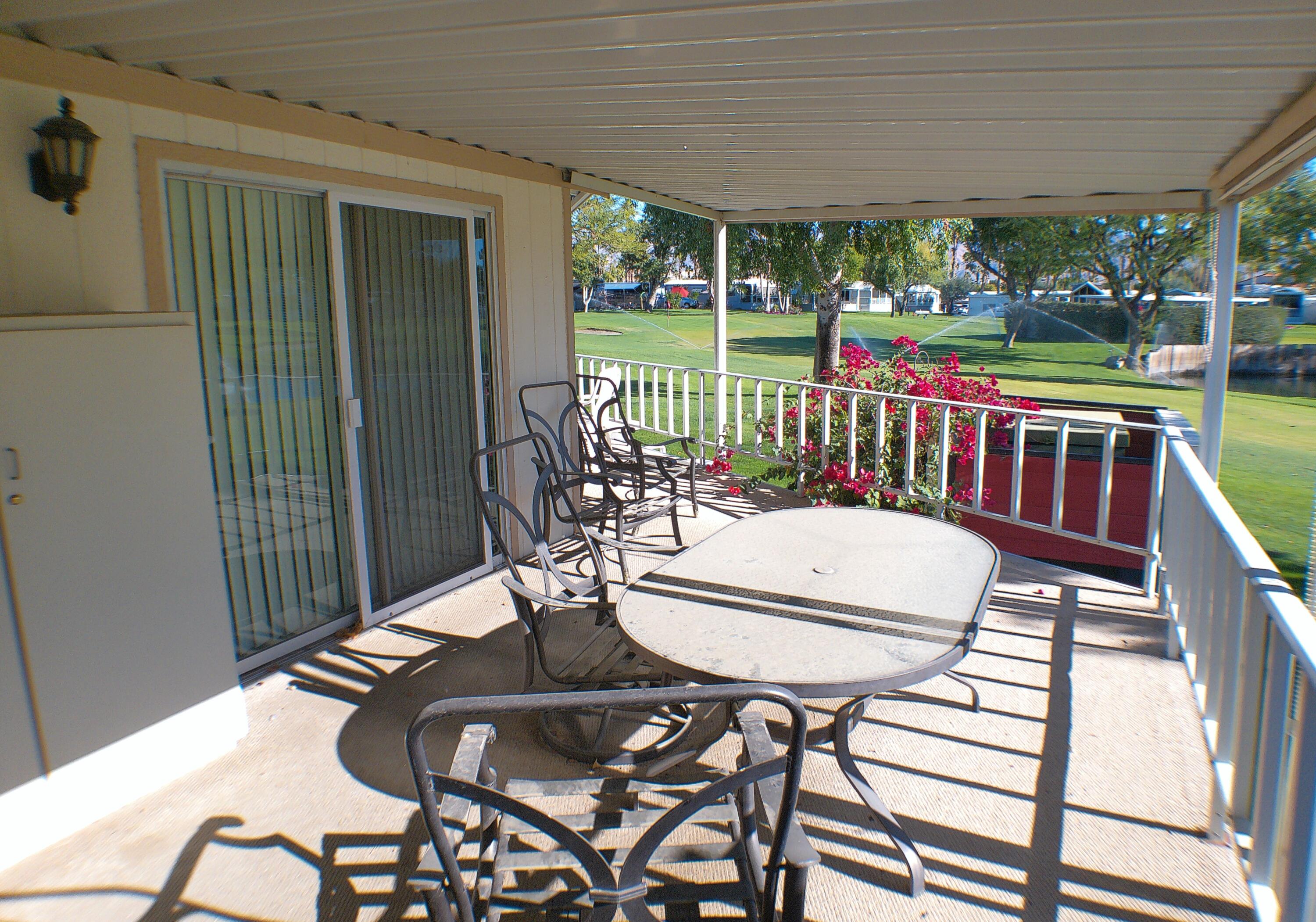 84136 Ave 44, Unit 337 Indio, CA 92203 - Photo 4 of 31 a view of a patio with table and chairs potted plants with wooden floor
