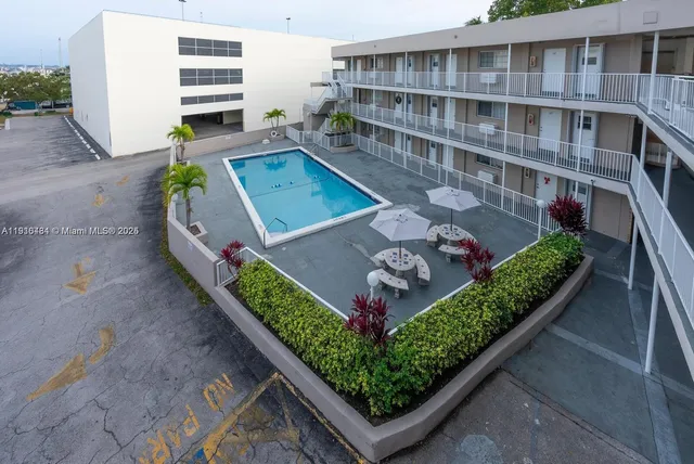a view of a white house with a couches and flower plants next to road