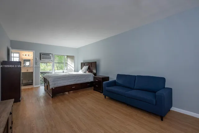a bedroom with a bed couch and wooden floor