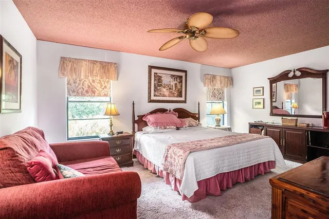 a view of a livingroom with wooden floor a ceiling fan and windows