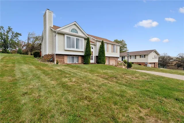 a view of a house with a big yard and large trees