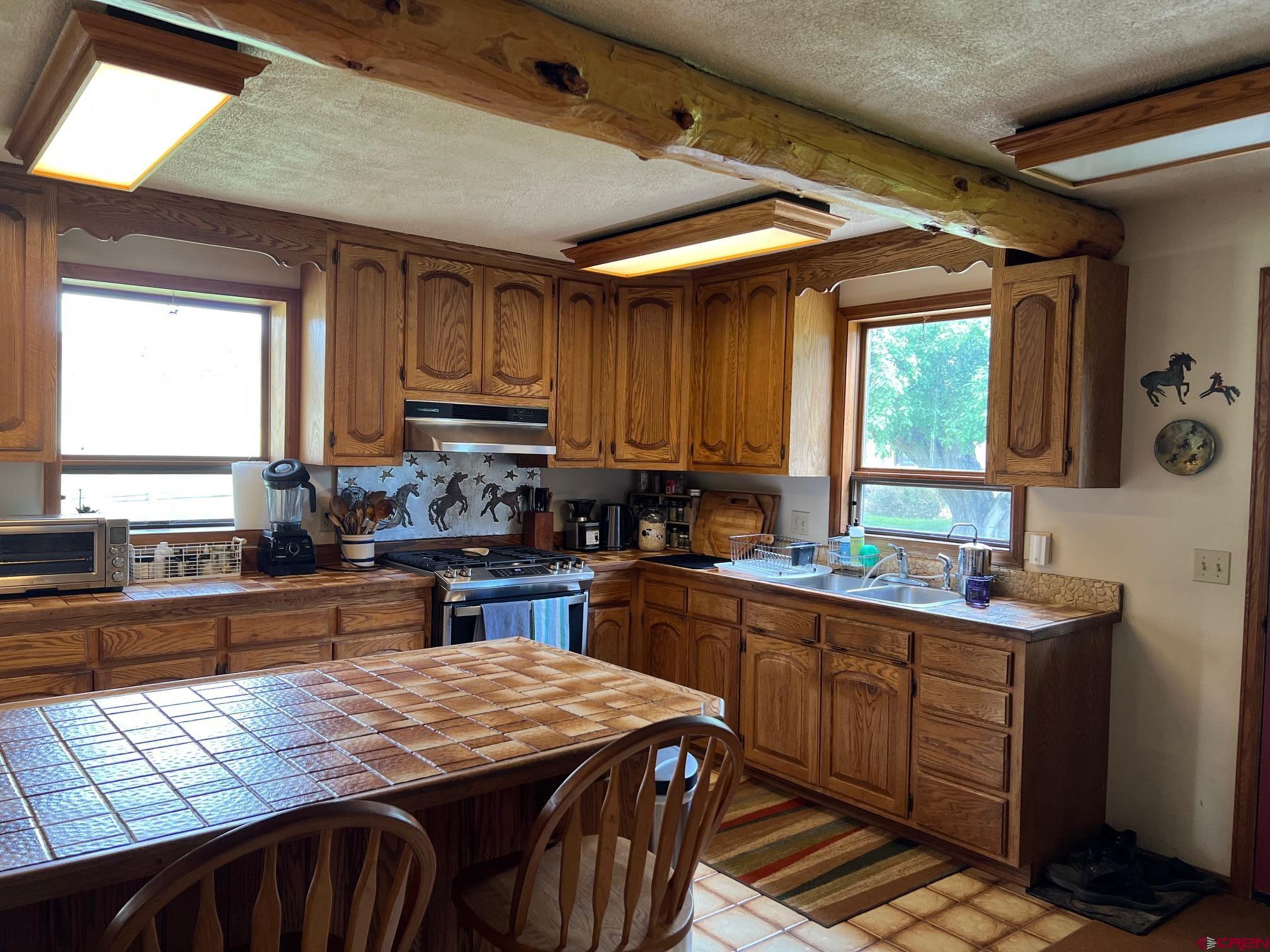 21446 Uncompahgre Road Montrose, CO 81403 - Photo 10 of 40 a kitchen with kitchen island granite countertop a sink stove and cabinets
