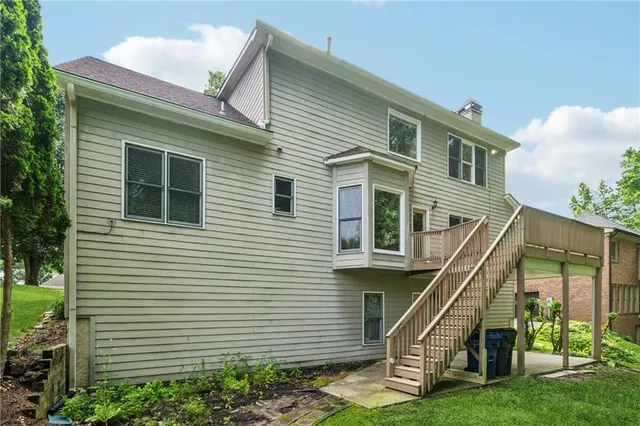 a view of a house with a small yard and wooden deck