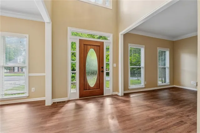 an empty room with wooden floor and windows