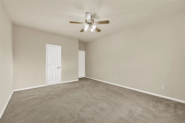 an empty room with chandelier fan and windows