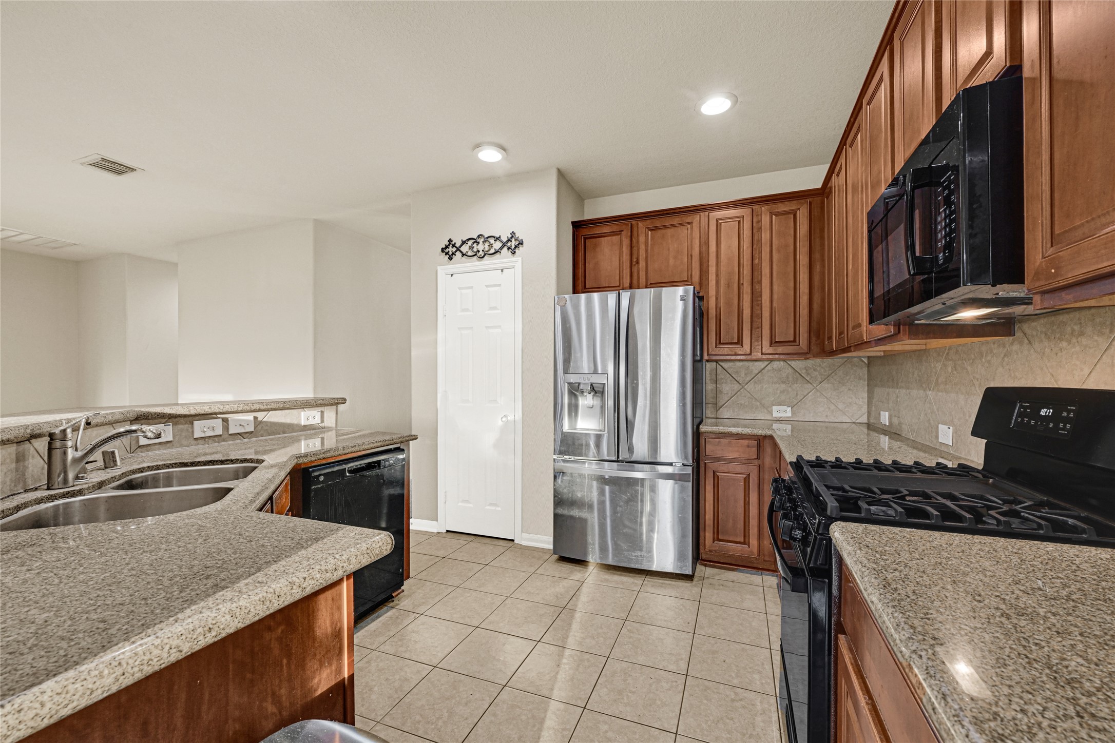 16415 Lapis River Drive Spring, TX 77379 - Photo 5 of 20 a kitchen with stainless steel appliances granite countertop a refrigerator a stove and a sink with wooden cabinets