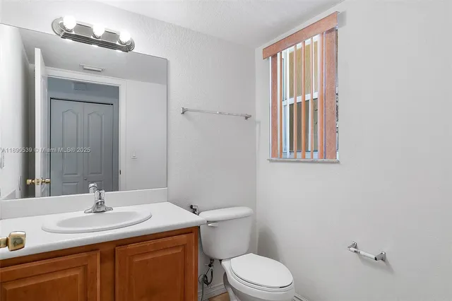 a bathroom with a granite countertop sink toilet and mirror