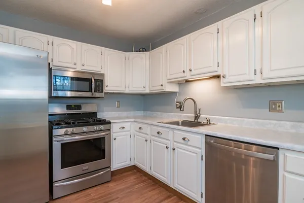 a kitchen with white cabinets and stainless steel appliances