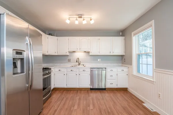 a kitchen with granite countertop a refrigerator sink and cabinets