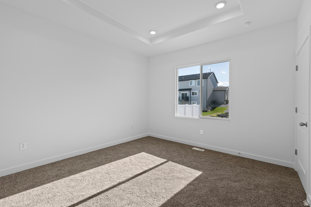 2823 North 710 West, Unit 16 Logan, UT 84321 - Photo 9 of 22 Spare room featuring dark carpet, recessed lighting, and a tray ceiling