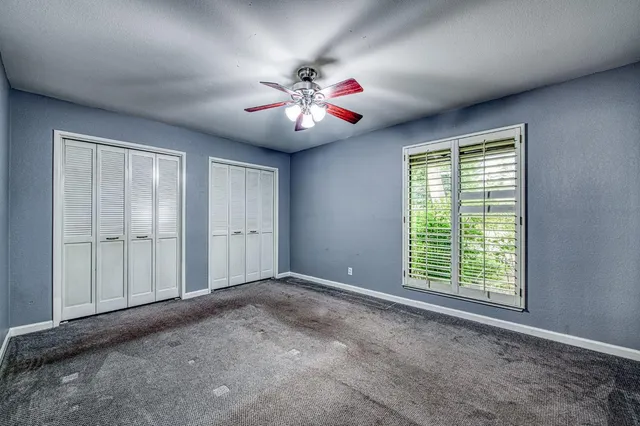 a view of an empty room with window and chandelier fan