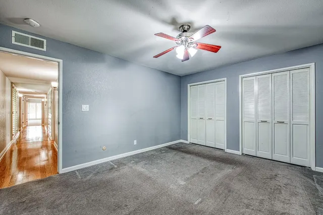 a view of an empty room with window and chandelier fan