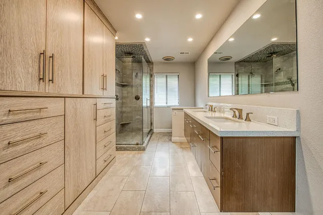 a bathroom with a double vanity sink a mirror and a shower