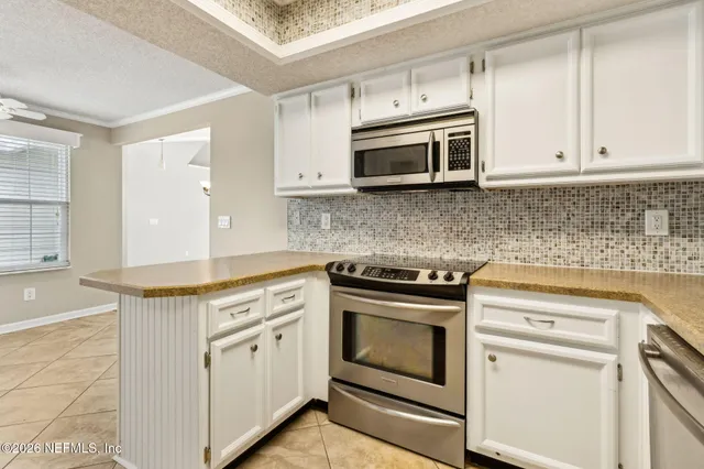 a kitchen with stainless steel appliances white cabinets and a stove top oven