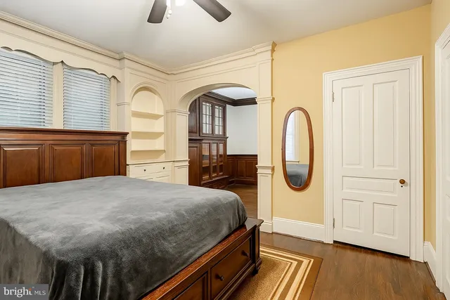a bedroom with a bed a mirror on dresser and a window