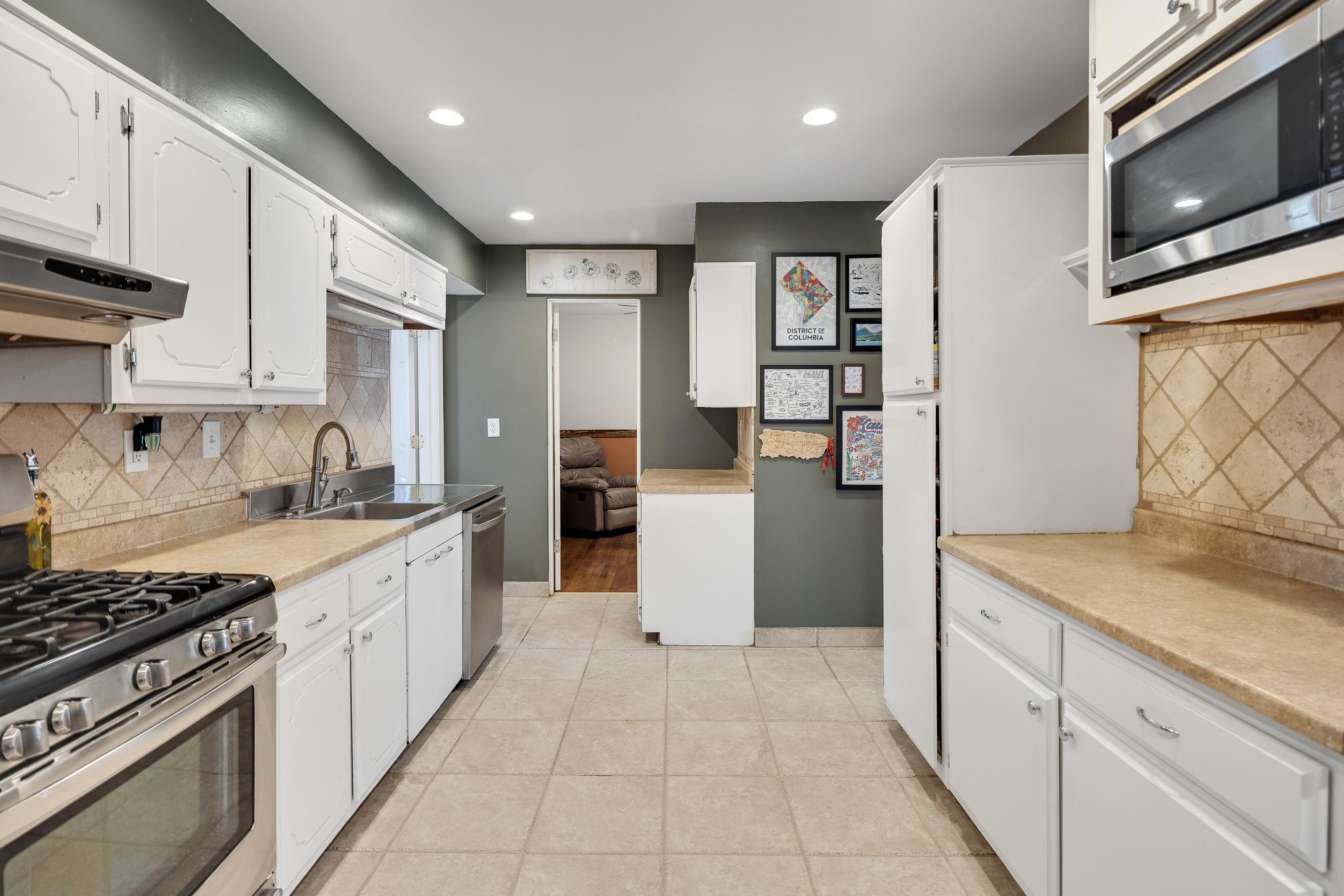 1130 Wilmore Road Memphis, TN 38117 - Photo 13 of 35 Kitchen featuring decorative backsplash, stainless steel appliances, white cabinetry, light countertops, and recessed lighting