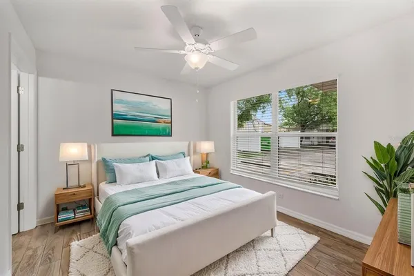 an empty room with wooden floor fan and windows