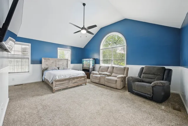 a bedroom with furniture a ceiling fan and a large window