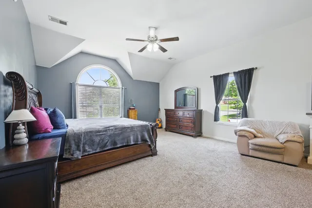 a spacious bedroom with a bed a couch and a large window with the outer view