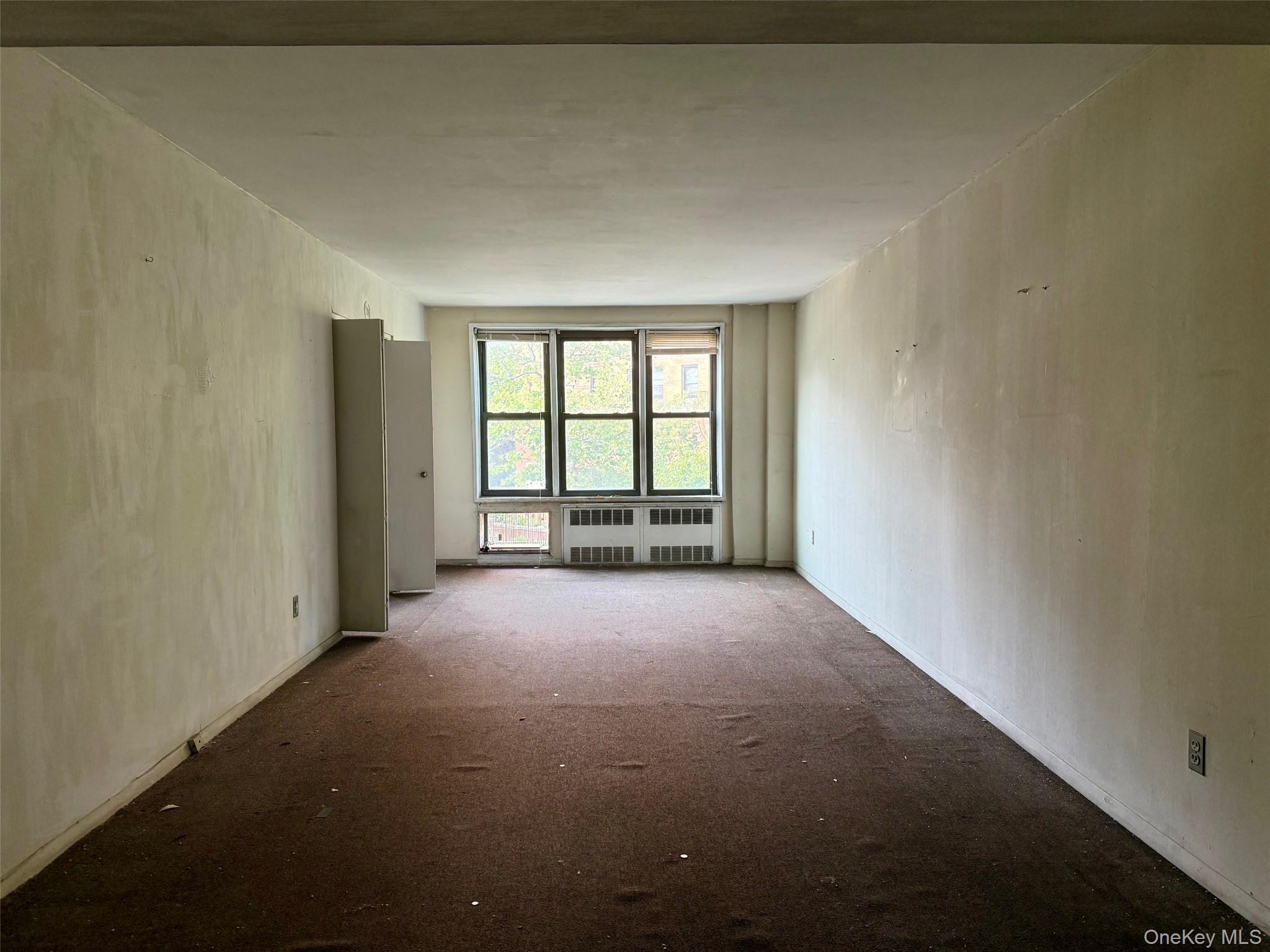 58-03 Calloway Street, Unit 3EE Queens, NY 11368 - Photo 10 of 20 Carpeted empty room featuring radiator heating unit