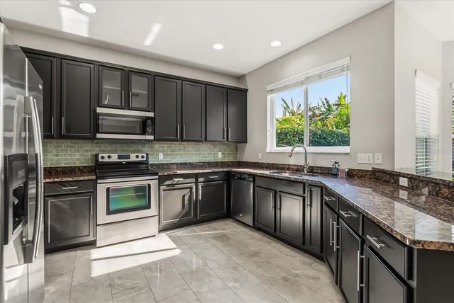 a kitchen with stainless steel appliances granite countertop a stove sink microwave and refrigerator
