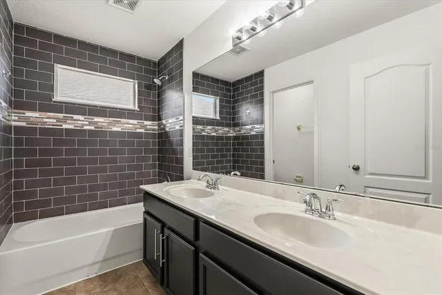 a bathroom with a granite countertop sink and a bathtub