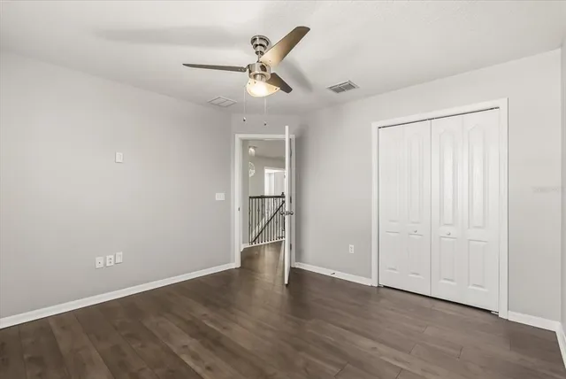 an empty room with wooden floor cabinet and a ceiling fan