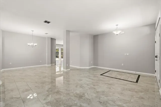 an empty room with an entryway and chandelier fan