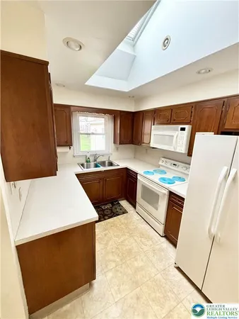 a kitchen with stainless steel appliances a refrigerator a sink dishwasher a oven with white cabinets and wooden floor